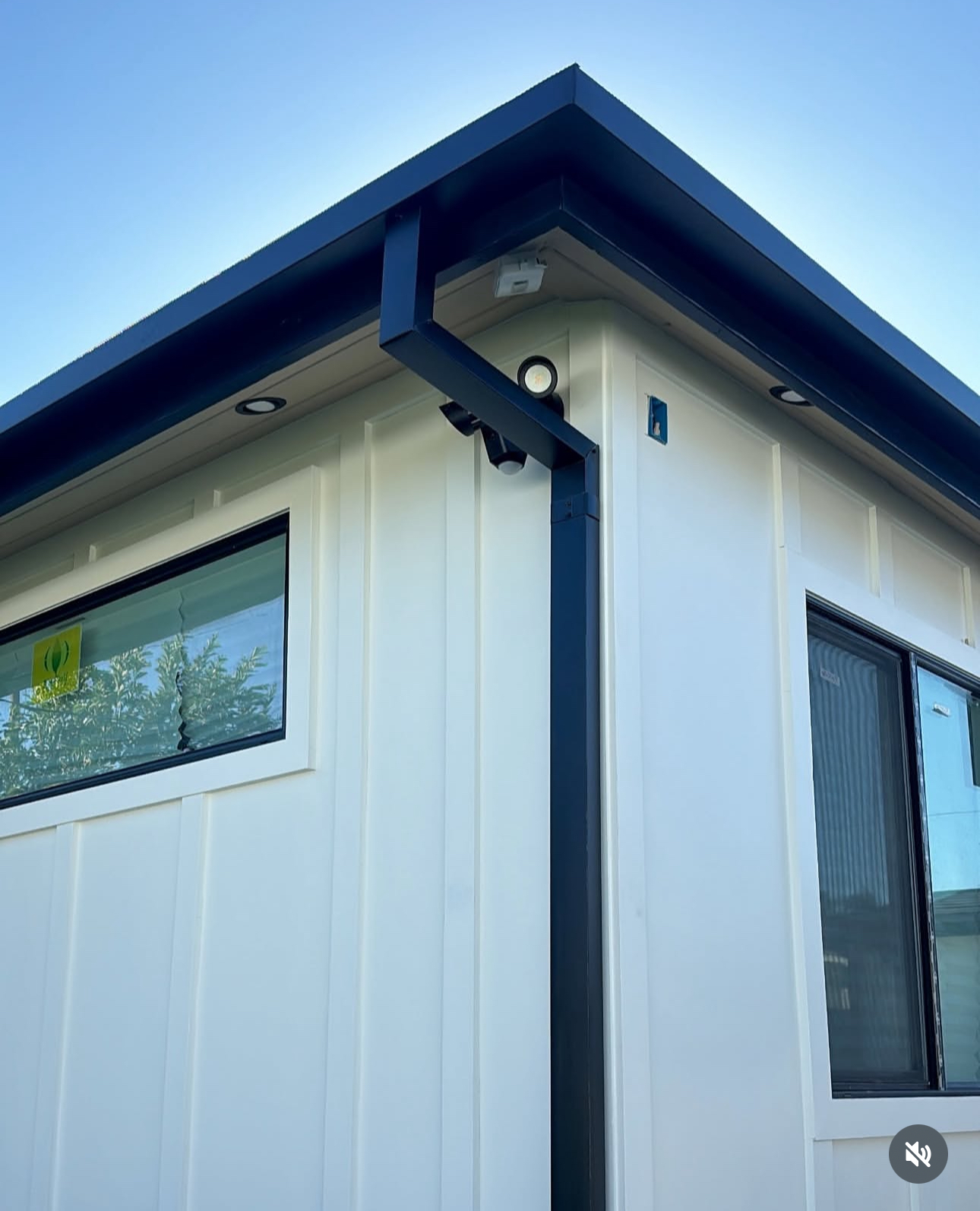 Dark gutter and downspout installed on a white home